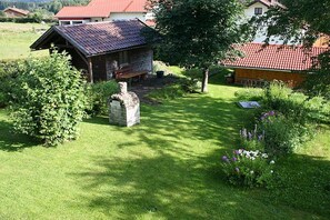 A rural setting with a stone structure, a wooden building with a red roof, and a well-maintained lawn. - 1 - Gertraud Weiderer (Lindberg)