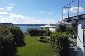 Blick auf einen Garten mit Rasen, Liegestuhl und Tisch.