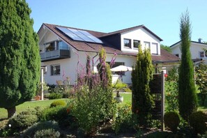 A two-story house with a sloped roof, solar panels, and a well-maintained garden with various plants and a small tree. - Herold holiday apartment (Friedrichshafen)
