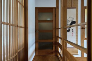 A narrow hallway with a wooden door and a wooden railing. - HETA Niseko [50-65% OFF for Weekly Stays | Sleeps Large Groups & BBQ Included] (ニセコ町)