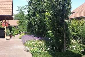 A garden pathway with potted plants and a variety of flowers. - Seedorf Hörster Heide (Warendorf)