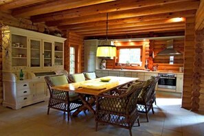 Interior de una cabaña de troncos con comedor, cocina y armarios empotrados.