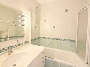 A bathroom with a sink, mirror, shower, and bathtub. - Croisette Immo  (Cannes)
