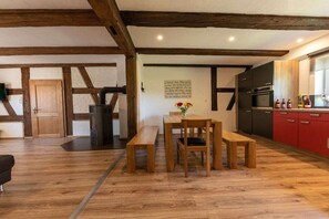 A modern kitchen with wooden beams, a dining area with a bench, and a red cabinet. - Holiday home in Ellingen with swimming pool (Ellingen)