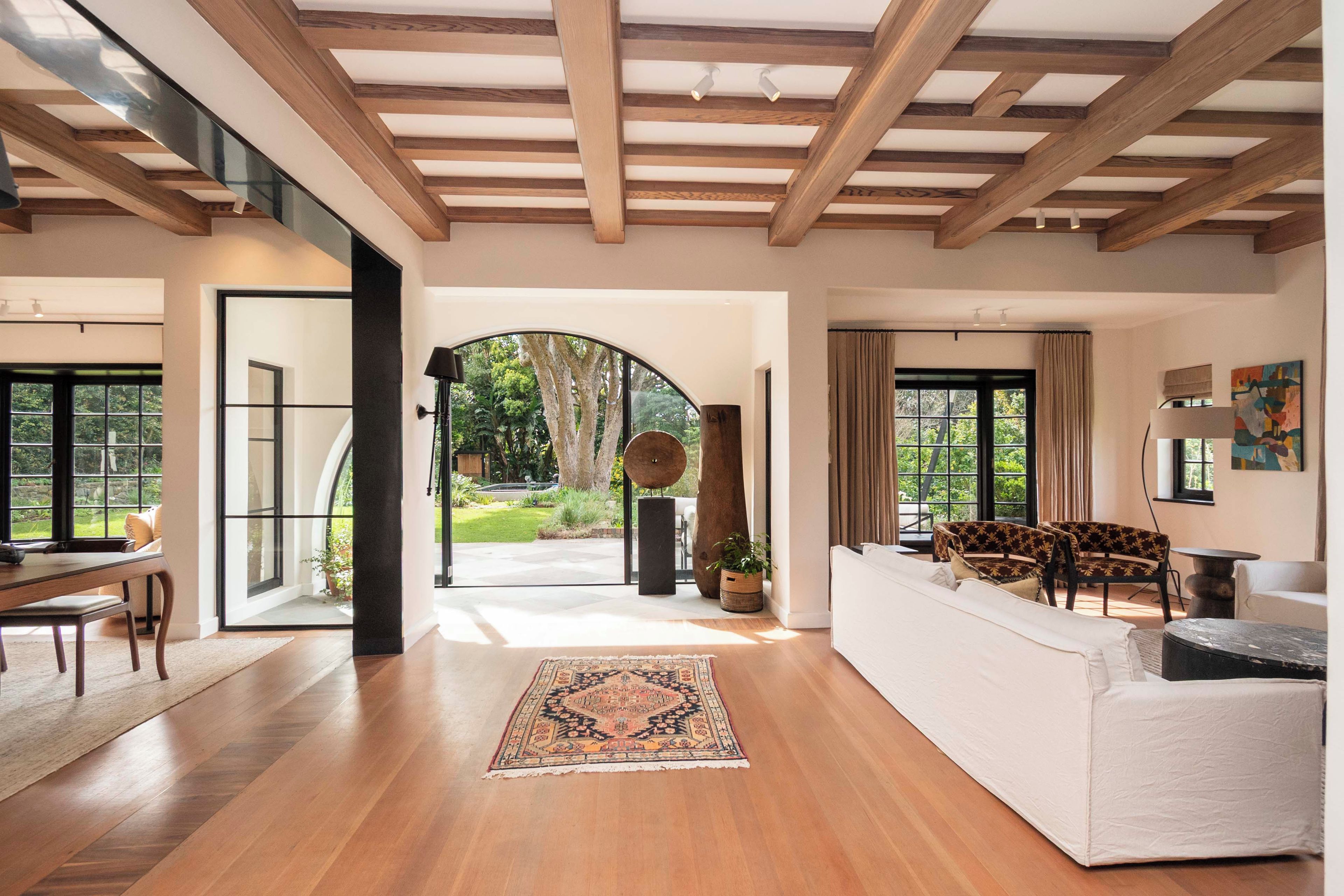 A spacious living area with a large window, a white sofa, and a wooden floor.