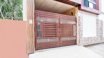 Una reja doble de metal con detalles decorativos y un sendero de hormigón que conduce a un edificio.