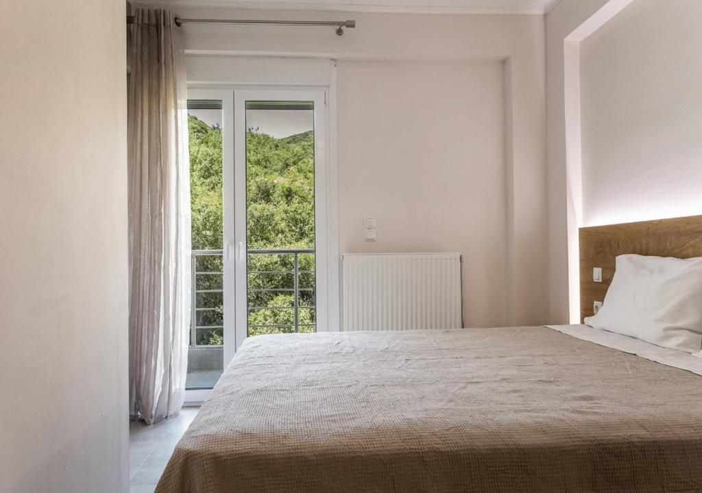 Un dormitorio con una cama grande, un radiador y vistas a zonas verdes a través de una puerta corredera.