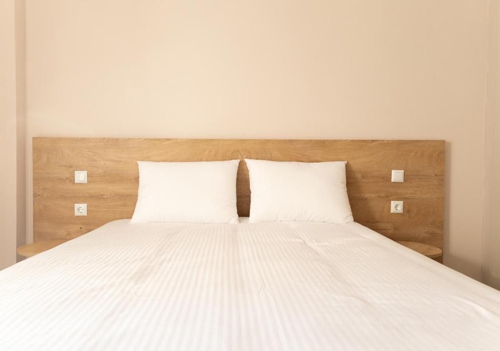 A bed with a wooden headboard and two white pillows.