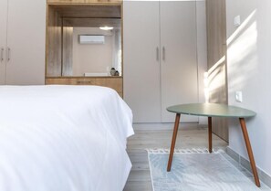 A bedroom with a bed, a small table, and a wardrobe.