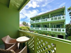 A balcony with wicker furniture and a view of a multi-story building with balconies. - HÙA Deluxe 104 (Đà Nẵng)