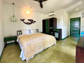 Un dormitorio con cama, armario, refrigerador pequeño y puerta verde.