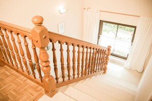 A wooden staircase with a balustrade leading to a room with a window and curtains. - Holiday home with 4 bedrooms (Ochtendung)