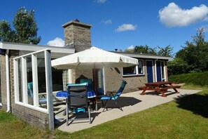 Une maison dotée d’un patio aménagé avec du mobilier d’extérieur et un espace salon couvert.