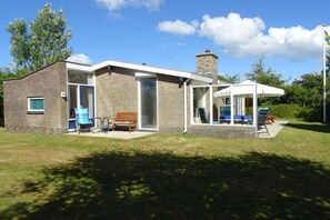 A modern house with a brick exterior, large glass doors, and a covered patio area. - Holiday apartment with 2 bedrooms (Ballum)