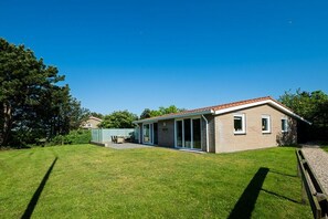 A single-story house with a covered patio, a lawn, and a clear blue sky. - Holiday home in Ballum with swimming pool (Ballum)