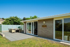 A residential property with a patio, a dining area, and a large sliding glass door. - Holiday home in Ballum with swimming pool (Ballum)
