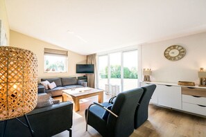 Een moderne woonkamer met een bank, salontafel en televisie.