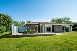 A modern house with a patio, a brick exterior, and a glass door entrance. - Holiday home in Ballum with swimming pool (Ballum)