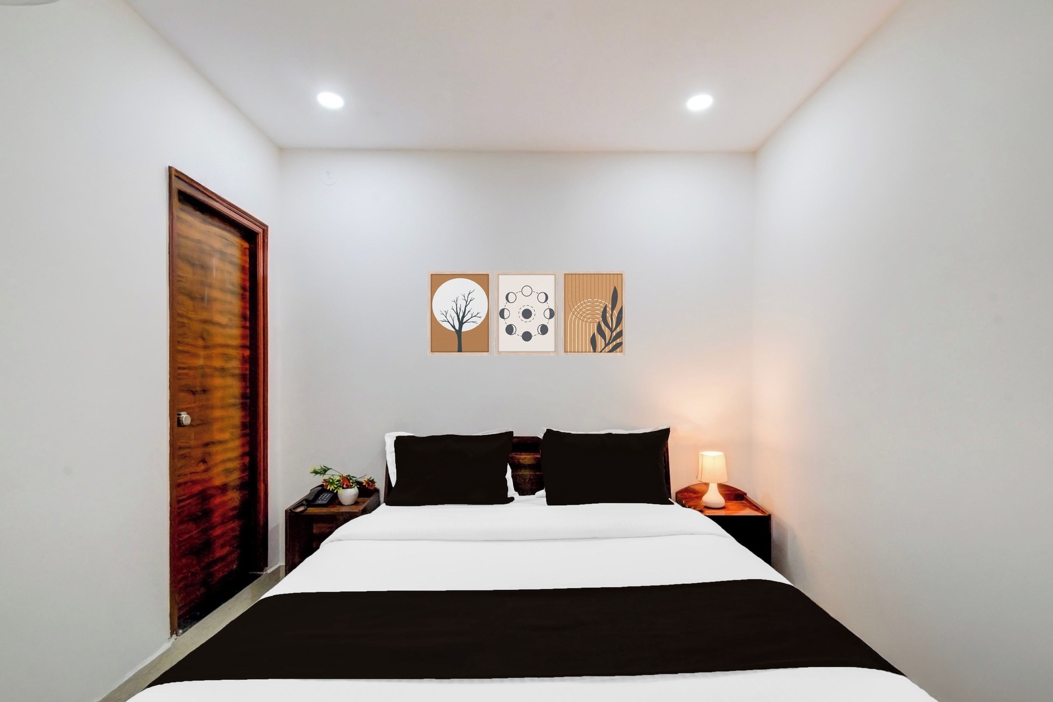 A bedroom with a bed, a nightstand, a lamp, and wall art.