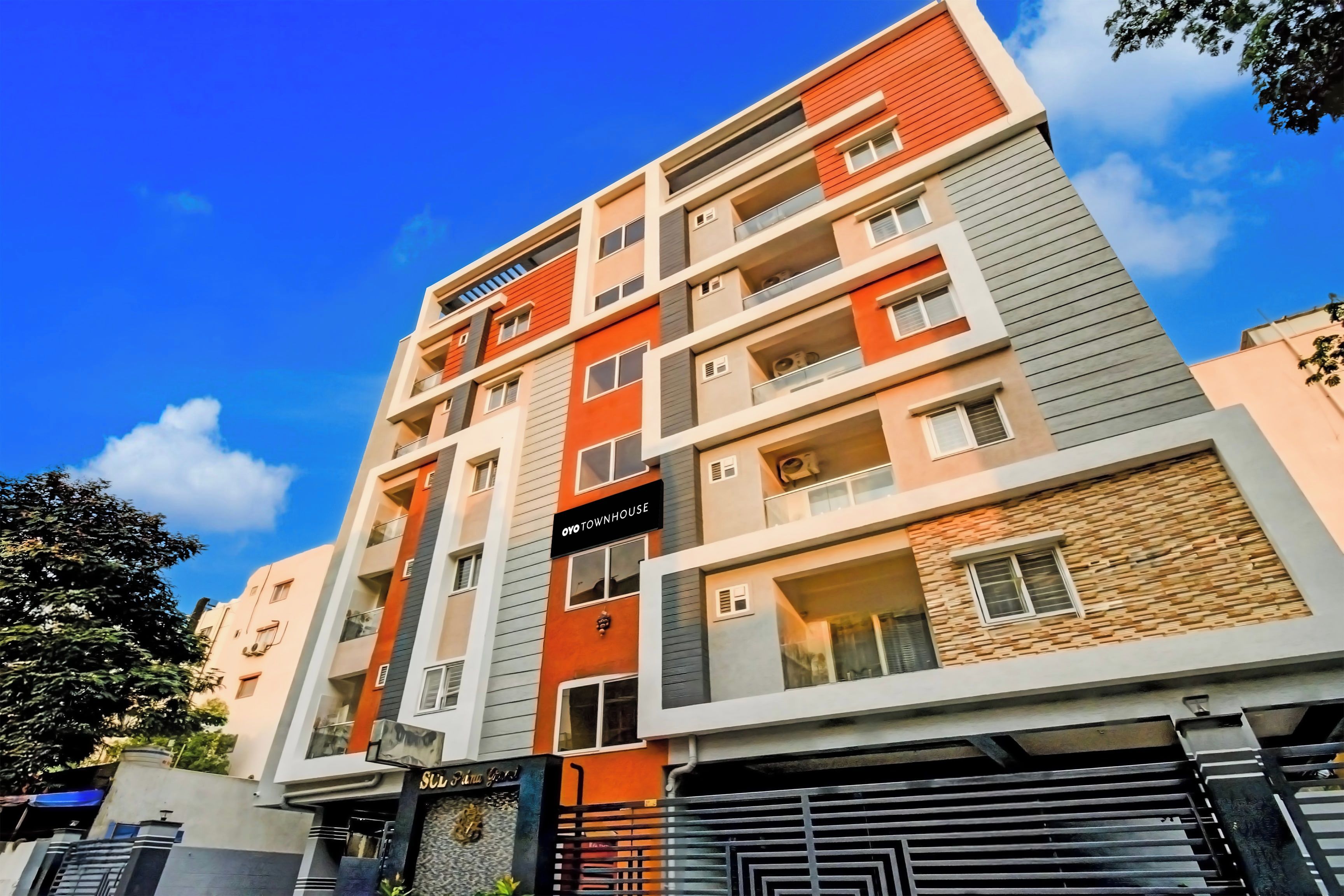 A multi-story residential building with balconies, a sign reading 'Oyo Townhouse,' and a gated entrance.