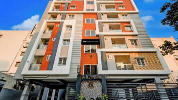 A multi-story building with balconies, a sign for 'OYO TOWNHOUSE,' and a 'SCL Prima Grand' entrance.