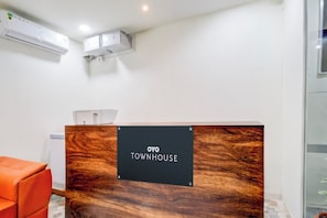 A reception desk with a sign reading 'OYO TOWNHOUSE' in a modern interior with a wooden finish. - Super Townhouse Nallagandla Nest  (Hyderabad)