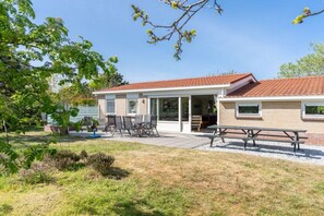 A residential building with a patio area, outdoor seating, and a visible garage. - Holiday apartment with 3 bedrooms (Ballum)