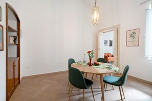 A dining area with a wooden table, four chairs, a vase with flowers, and a hanging light fixture. - Apartment 'Casa Cado'' (Bari)