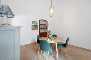 A dining area with a round table, four chairs, a lamp, a hanging light fixture, and a bookshelf. - Apartment 'Casa Cado'' (Bari)