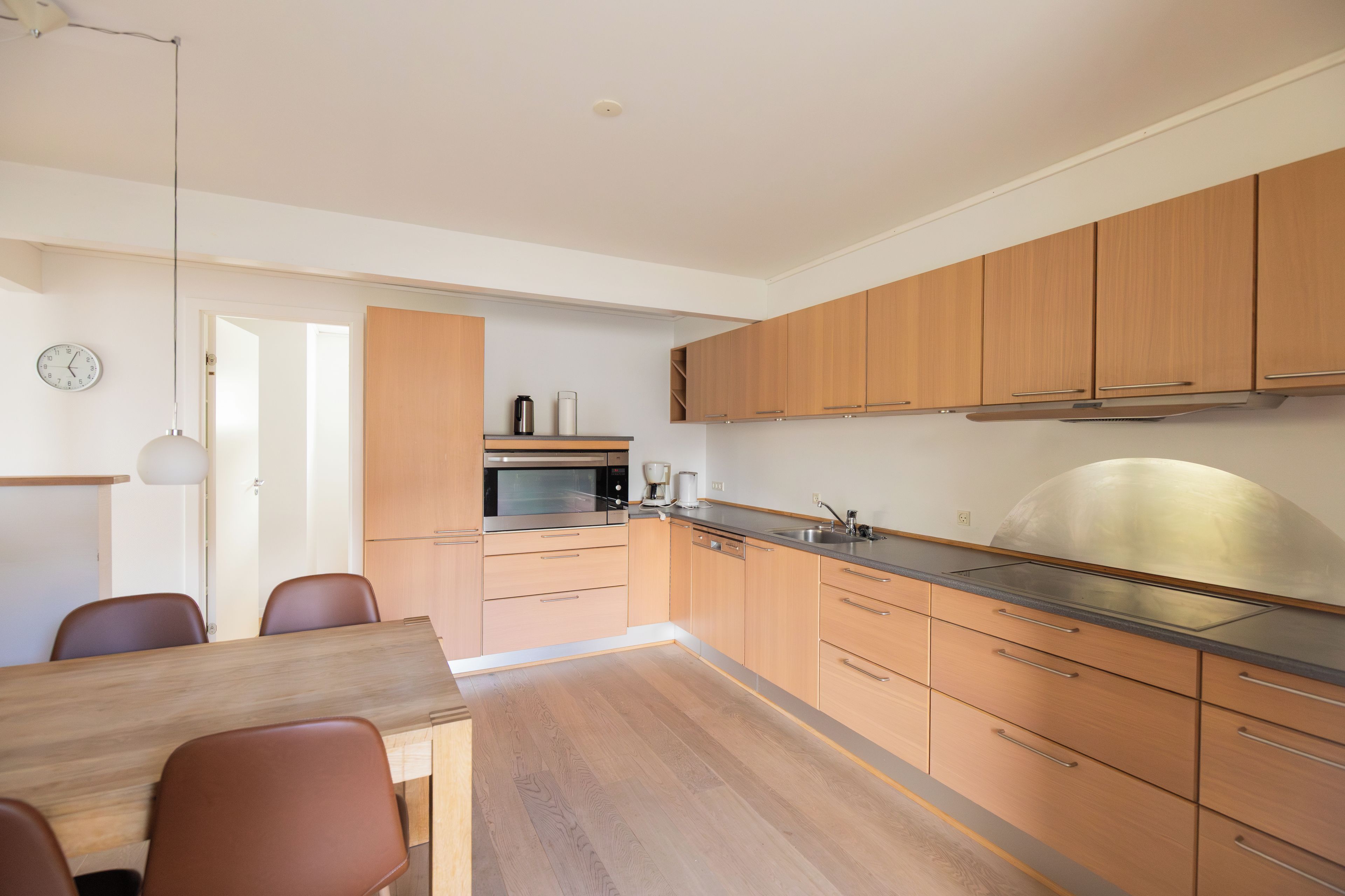 A modern kitchen with wooden cabinets, a stainless steel sink, and a built-in oven.