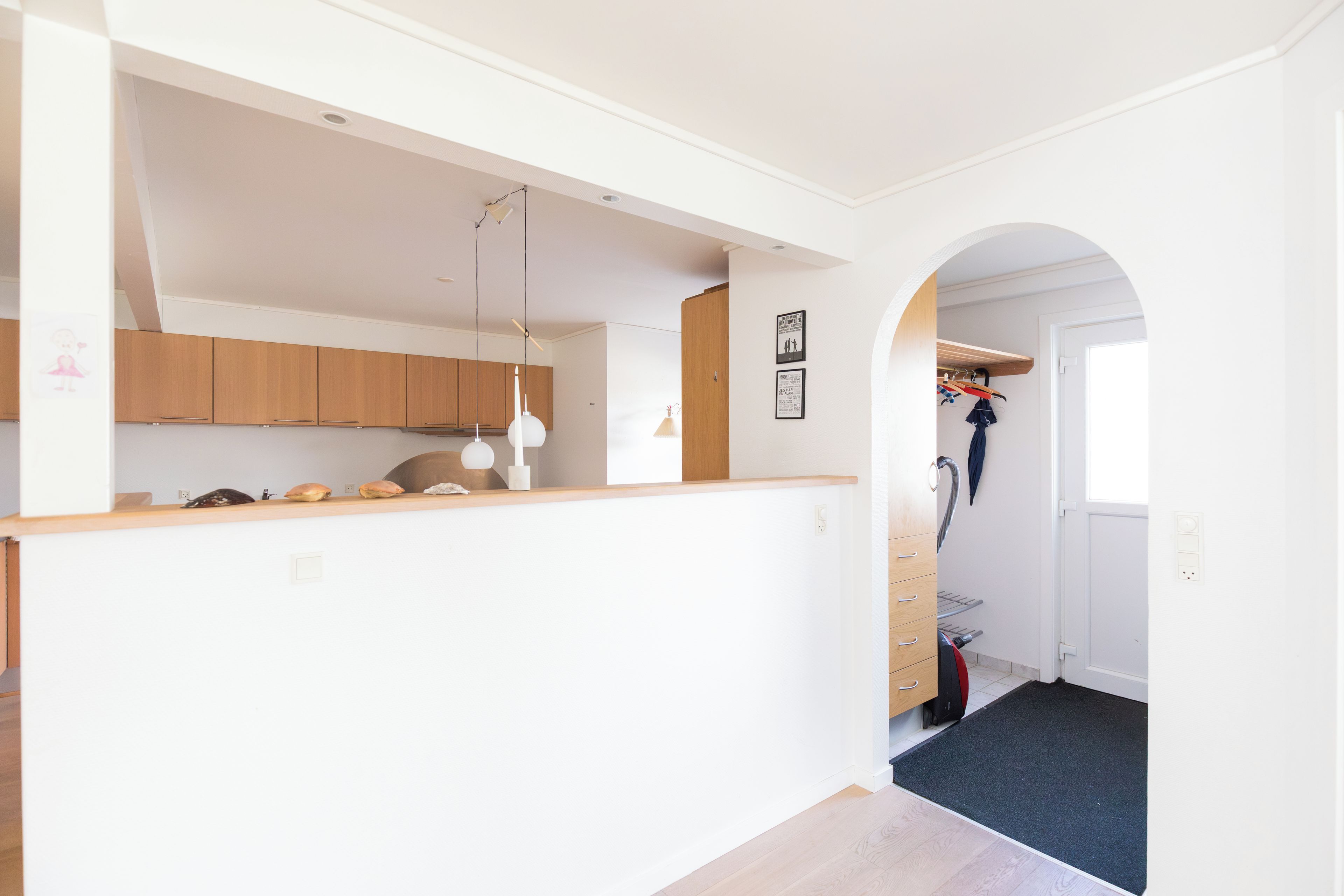 A modern kitchen with wooden cabinets, a countertop, and a hanging light fixture.