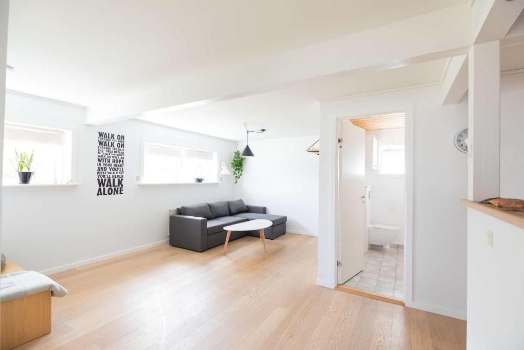 A modern living room with a grey sofa, a small white table, and a black pendant light.