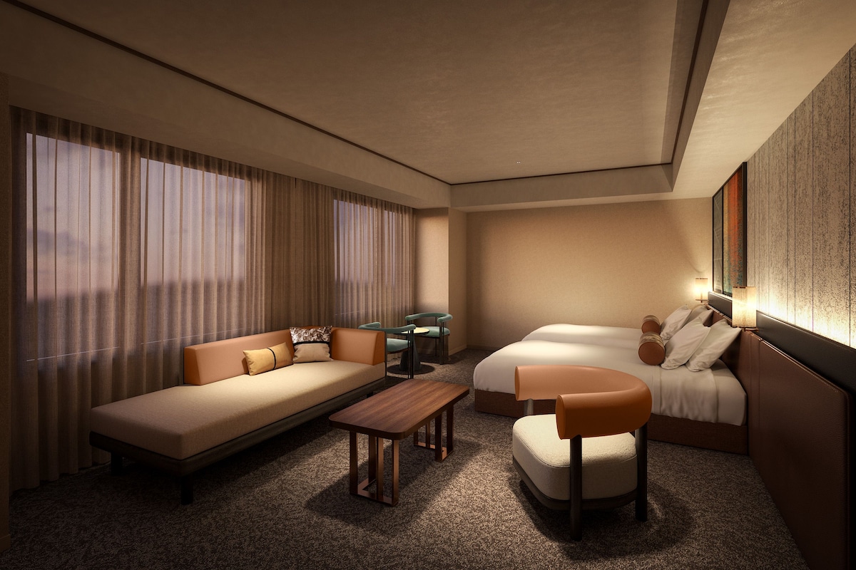 Een moderne hotelkamer met een bank, een enkel bed, een klein tafeltje en een stoel.