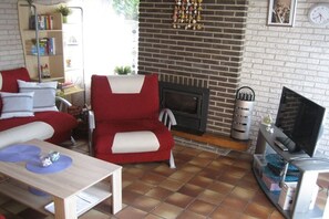 A living room with a fireplace, a sofa, a television, and a bookshelf. - Beach holiday and sea (St. Maartensvlotbrug)
