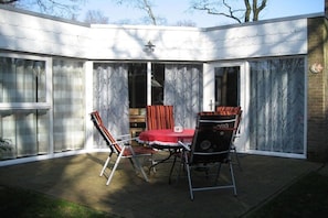 A patio with a table and chairs, a red tablecloth, and a grill. - Beach holiday and sea (St. Maartensvlotbrug)