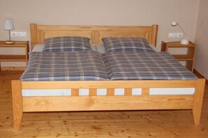 A wooden bed with a plaid bedspread and two bedside tables with lamps. - Farmhouse in Bachstrasse (Kelberg-Zermüllen)