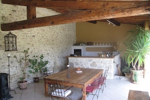 A rustic outdoor dining area with a stone wall, wooden beams, and potted plants. - with private pool in the Luberon - 223 ROU (Roussillon)