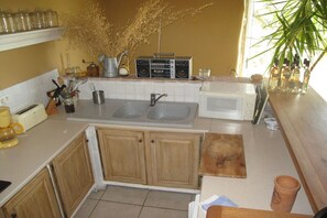 A kitchen with wooden cabinets, a double sink, a radio, and various kitchen utensils. - with private pool in the Luberon - 223 ROU (Roussillon)