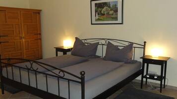 Una camera da letto con una struttura letto in metallo, due comodini con lampade, un armadio in legno e un quadro appeso al muro.