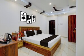 A modern hotel room with a wooden bed, a nightstand, a coffee maker, and framed artwork on the wall.