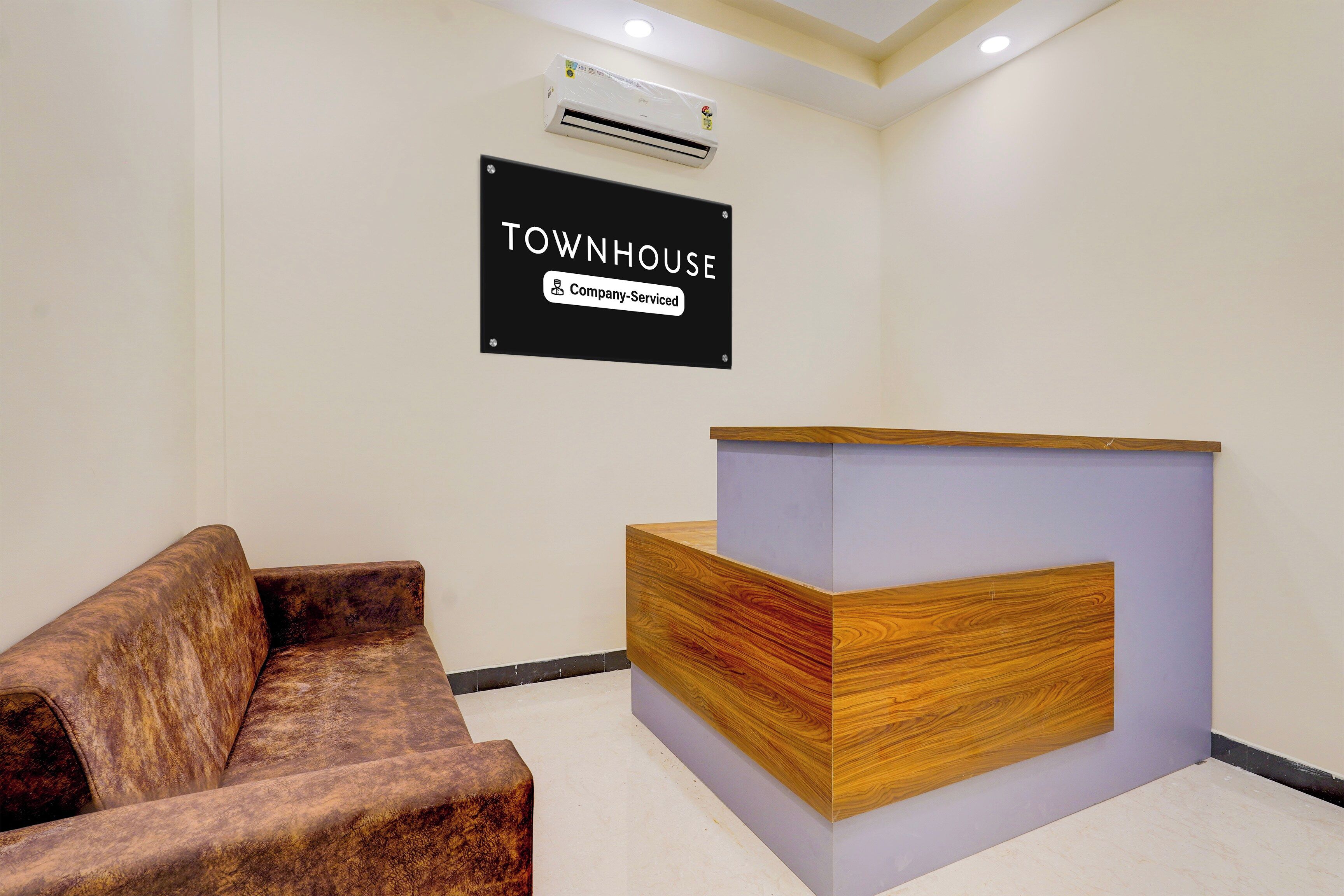 Zona de recepción con un cartel que dice 'TOWNHOUSE Company-Service' y un mostrador de recepción de madera.