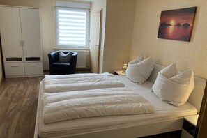 Ein Schlafzimmer mit Bett, Stuhl, Kleiderschrank und einem Bild an der Wand.