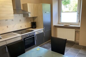 Eine kompakte Küche mit Gasherd, Backofen und integriertem Geschirrspüler. Ein Fenster sorgt für natürliches Licht und bietet Blick ins Grüne.