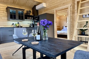 A modern interior with a dining table, two chairs, a vase with flowers, and a wine bottle.