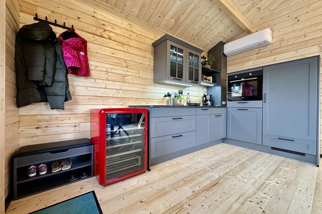 Eine kleine Küche mit Holzwänden, einem eingebauten Backofen und einem Kühlschrank.