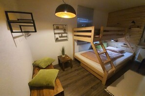 A compact room with a bunk bed, a small bedside table, a wall-mounted shelf, and a hanging light fixture. - Panoramic view of Baiersbronn (Baiersbronn)