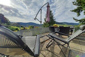 An outdoor patio with a table and chairs, a pergola with an umbrella, and a view of the countryside. - Panoramic view of Baiersbronn (Baiersbronn)
