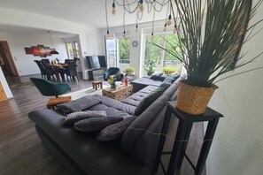 A modern living room with a sofa, a coffee table, and a large potted plant. - Panoramic view of Baiersbronn (Baiersbronn)