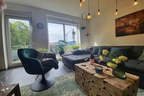 A modern living room with a sofa, a chair, a wooden coffee table, and a view of the outdoors. - Panoramic view of Baiersbronn (Baiersbronn)