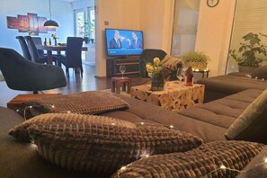 A living room with a sofa, a television, and a dining area in the background. - Panoramic view of Baiersbronn (Baiersbronn)